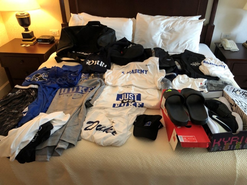 Lots of athletic clothing on a bed.